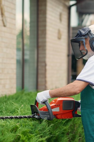 man-wearing-ear-face-defenders-cutting-bushes-min